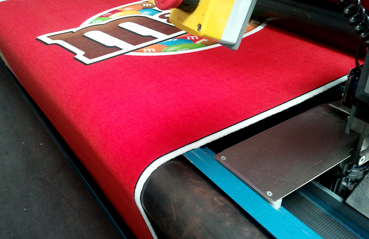 Printed felt carpet with anti-slip backing coming off a production roller